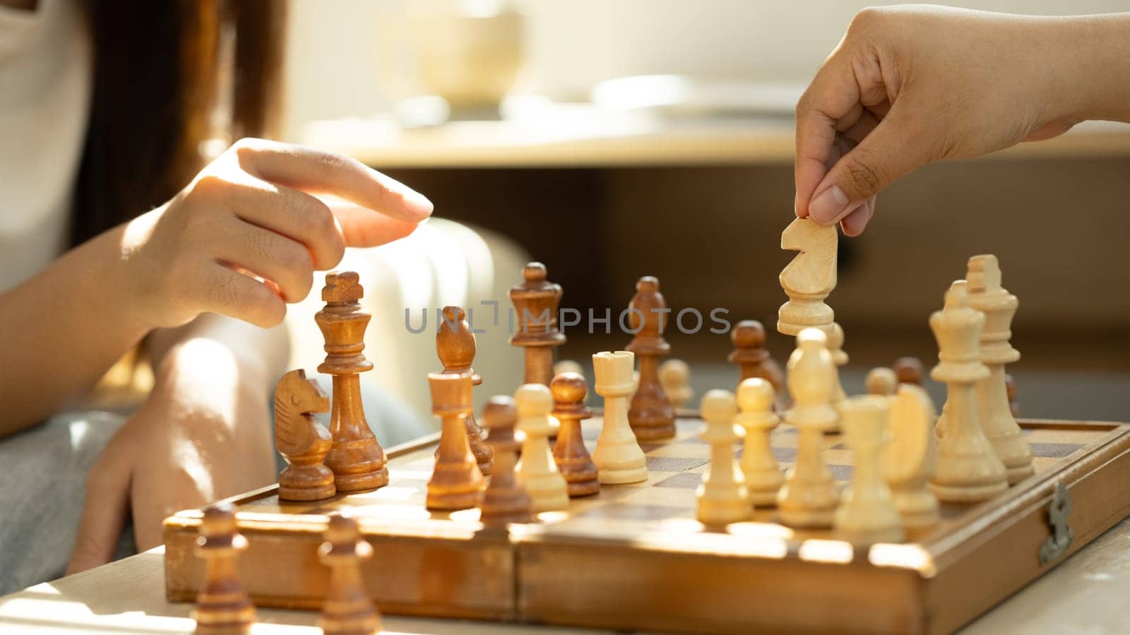 Close up of friends playing chess under warm natural light.