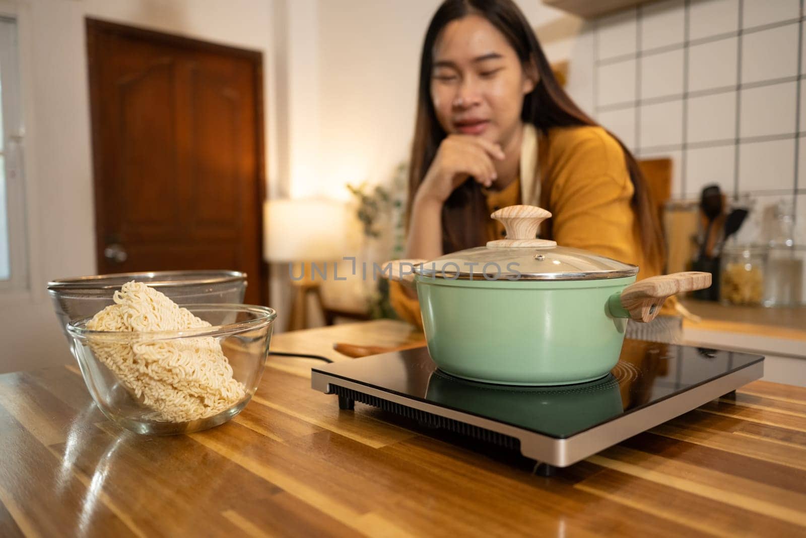 Happy asian woman in an apron stands in a kitchen, preparing a quick and easy meal.
