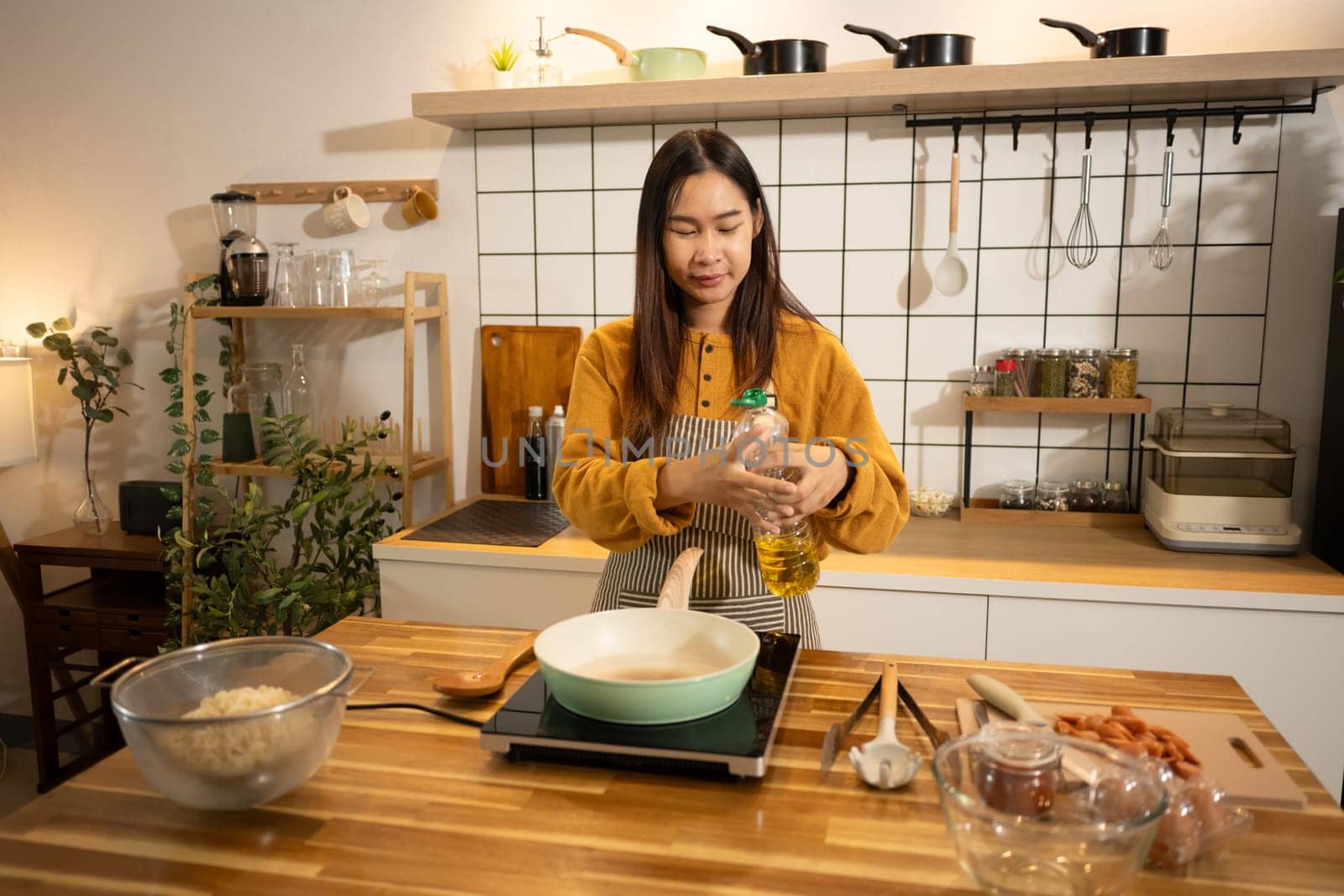 Happy asian woman in apron preparing meal in a stylish home kitchen.