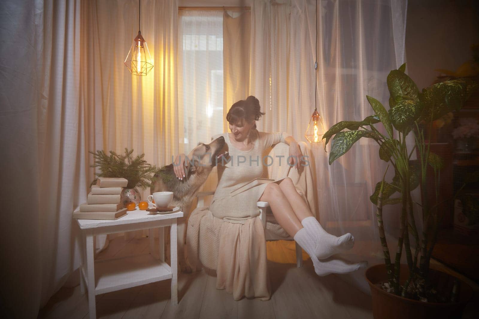 A middle-aged woman relaxes in a cozy apartment, seated comfortably with her dog, enjoying a peaceful evening filled with comfort.