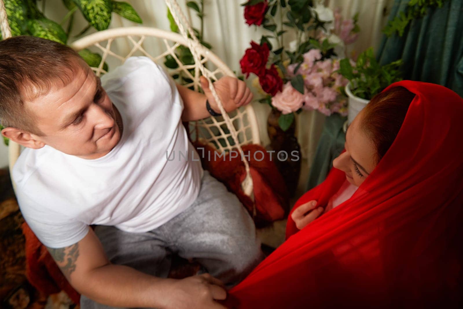 A loving couple engages in humorous role-playing while dressed in colorful oriental outfits, sharing joyful moments.
