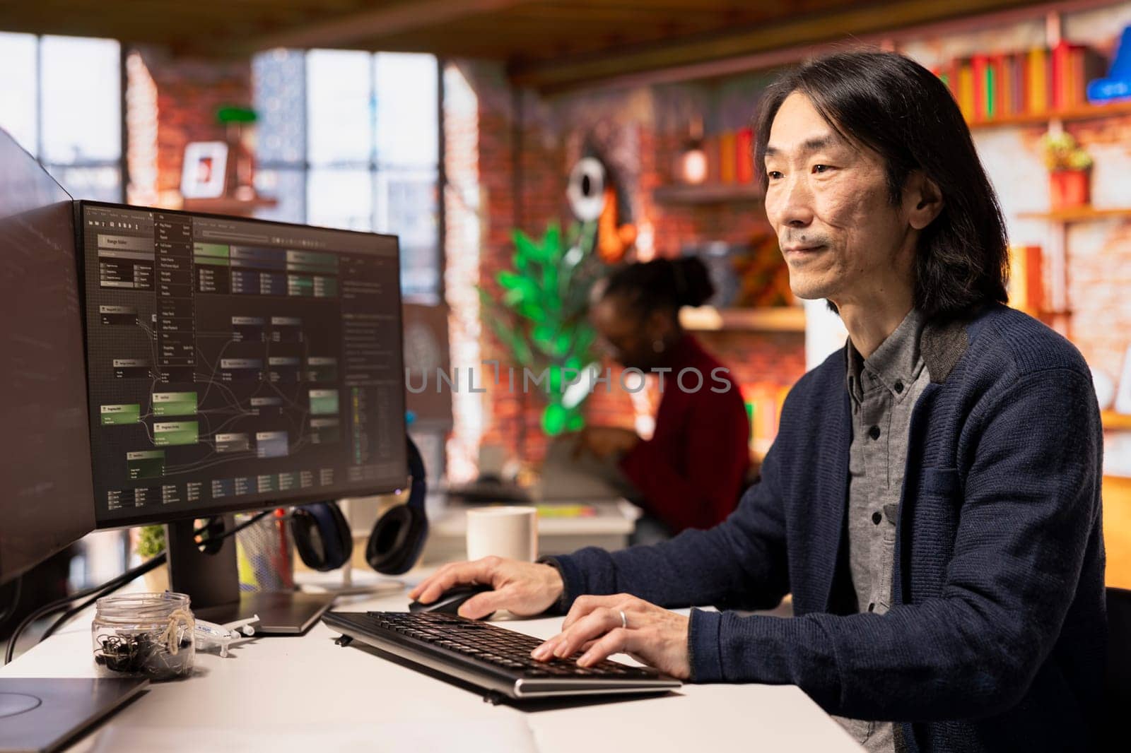 Senior technician coding advanced AI algorithm in startup office, refining machine learning models to enhance automation. Asian CTO manager using coding platform in Silicon Valley workplace