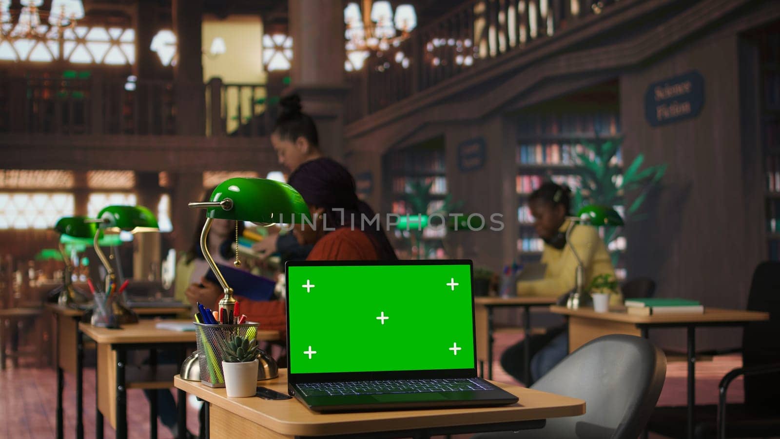 Diverse schoolgirls work with professors on homework next to mockup screen, focused on writing an essay in a school library. Scholars completing their assignment on textbooks. Camera A.