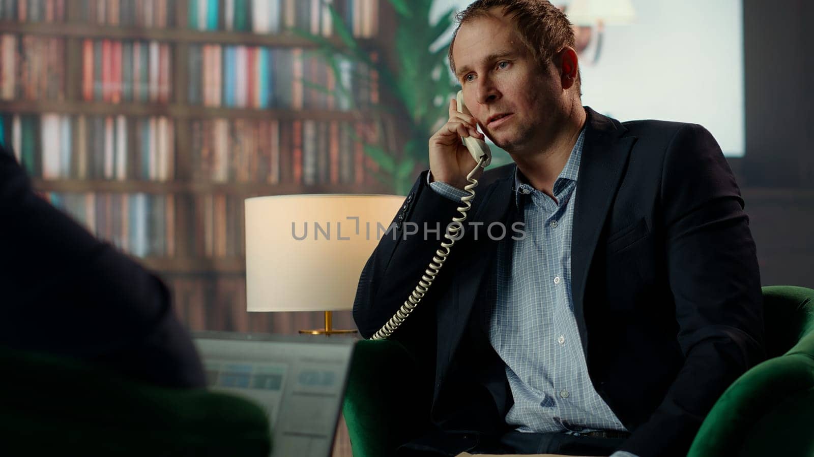 Intelligence officer on a secure line answering phone call in CIA safe house, gathering field information from undercover informants scattered around the city. Sensitive details. Camera B.