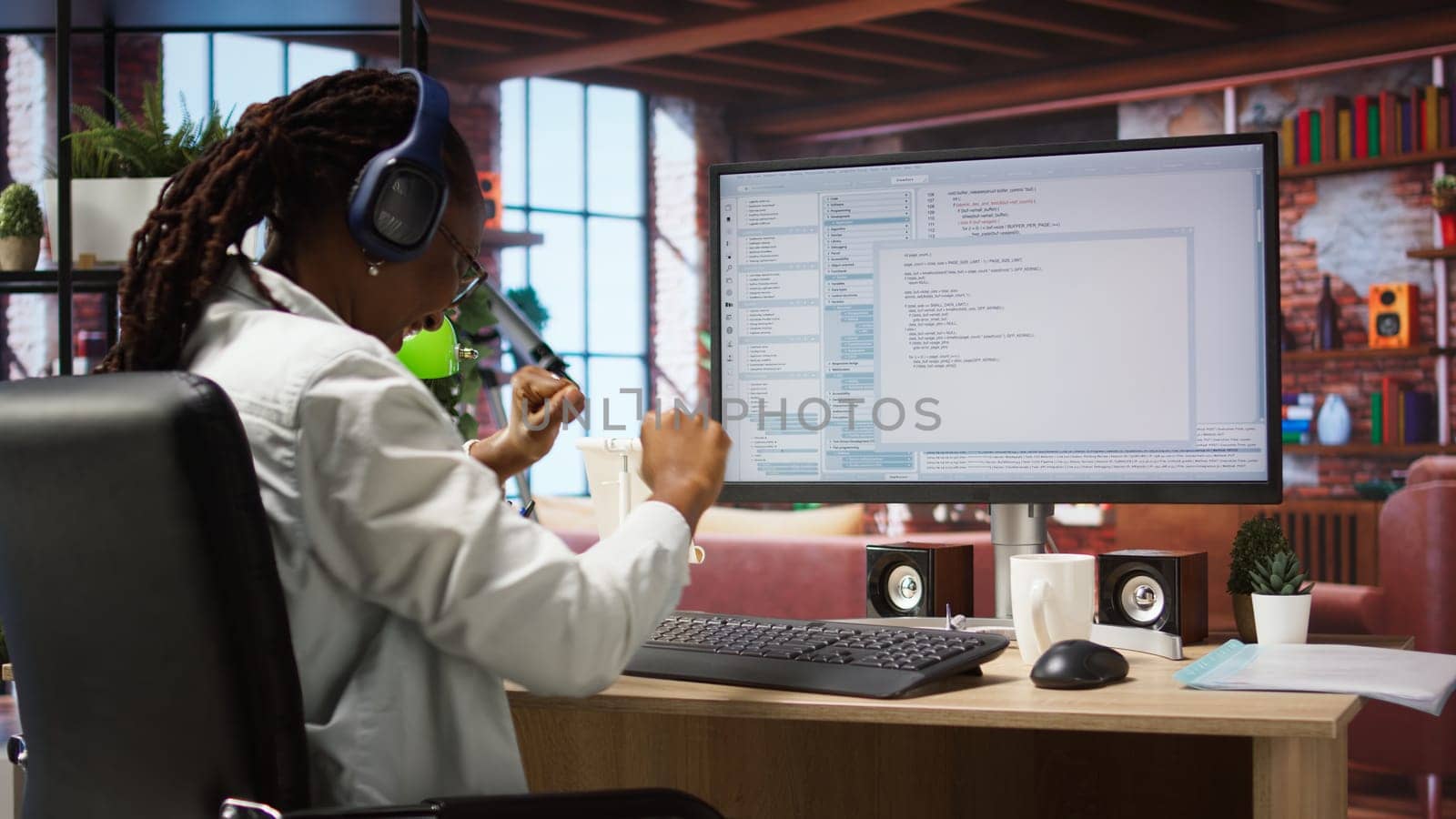 Cheerful software developer at computer waiting for code to finish compiling, celebrating after managing to make it run without errors. Woman happy after finishing work on algorithm scripts, camera A