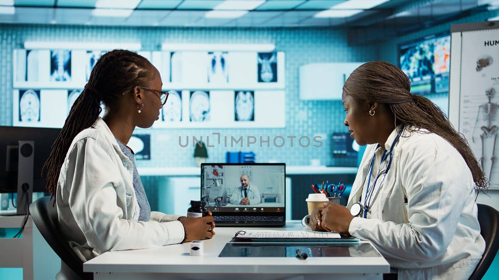 Physician calling the expert practitioner on video conference with a patient, creating a telehealth consultation for a second opinion. Medical staff using high tech equipment at clinic. Camera B.