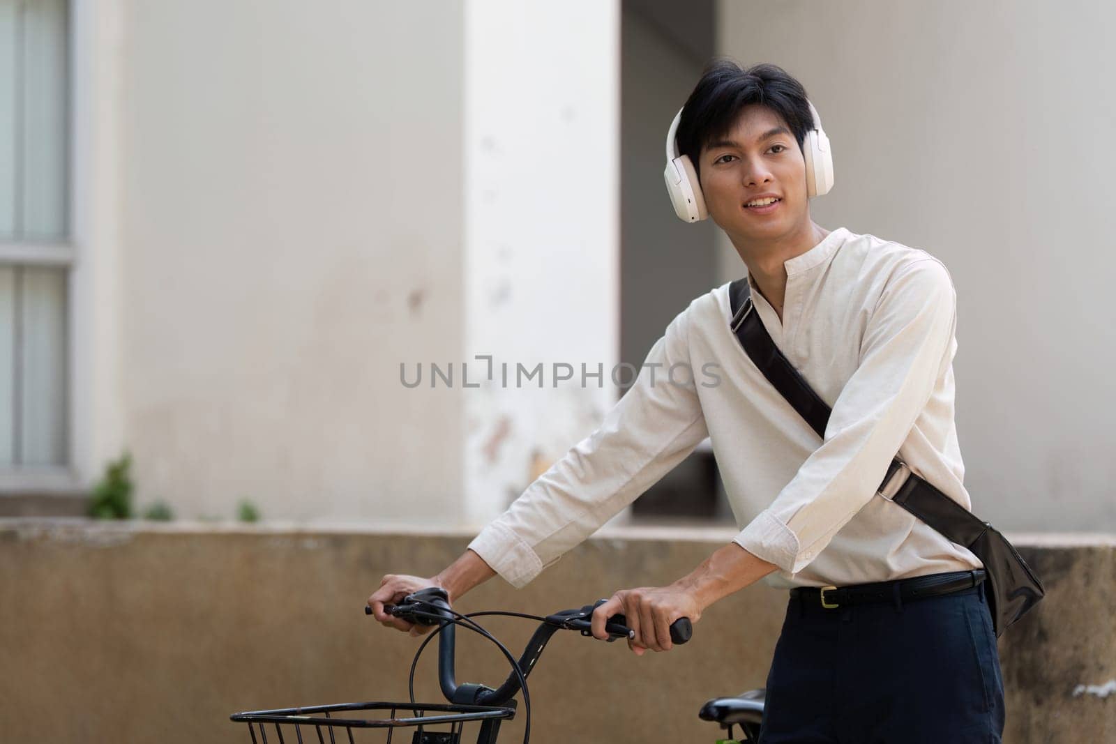 A young man with headphones cycles through an urban area, reflecting a modern lifestyle centered on sustainability and fitness.