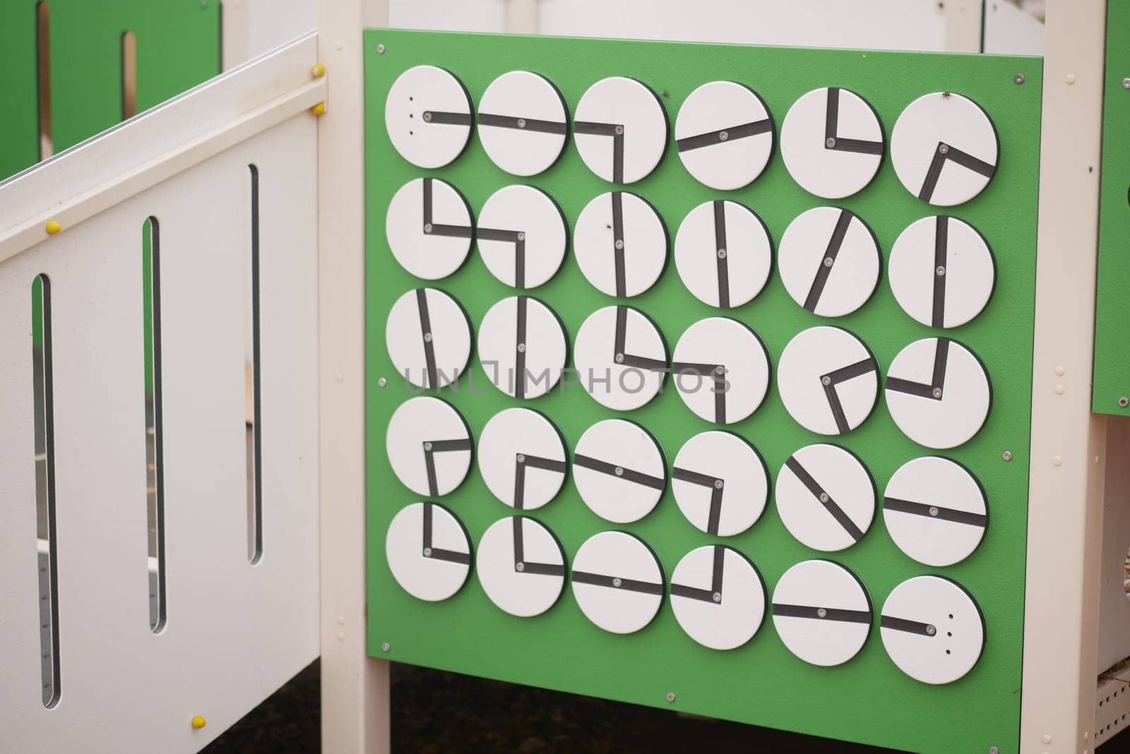 Children eagerly explore a clock face activity at a playground.