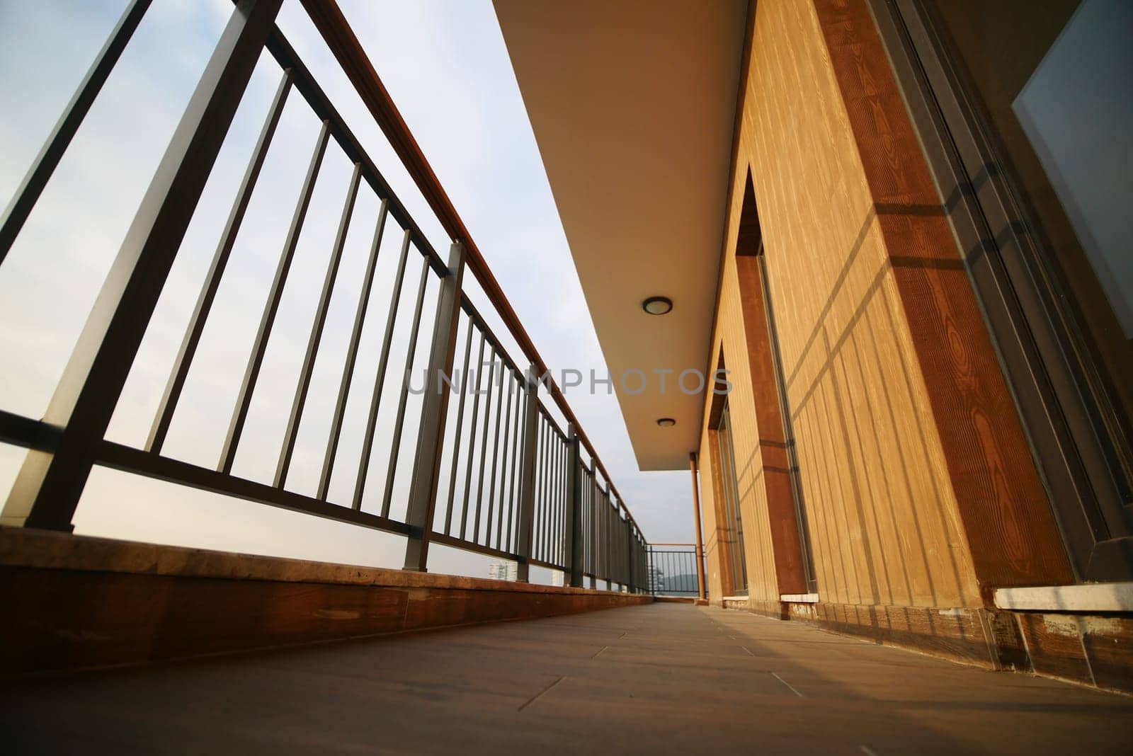 A spacious balcony offers a panoramic view of the horizon at twilight.
