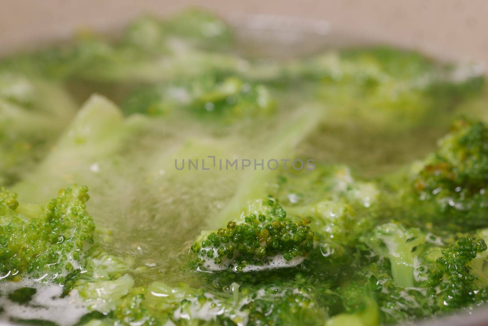 Fresh broccoli is being boiled until tender in a pot of water.