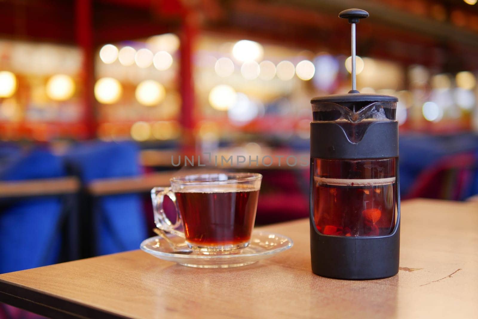 Freshly brewed coffee and tea sit on a table in a warm cafe.