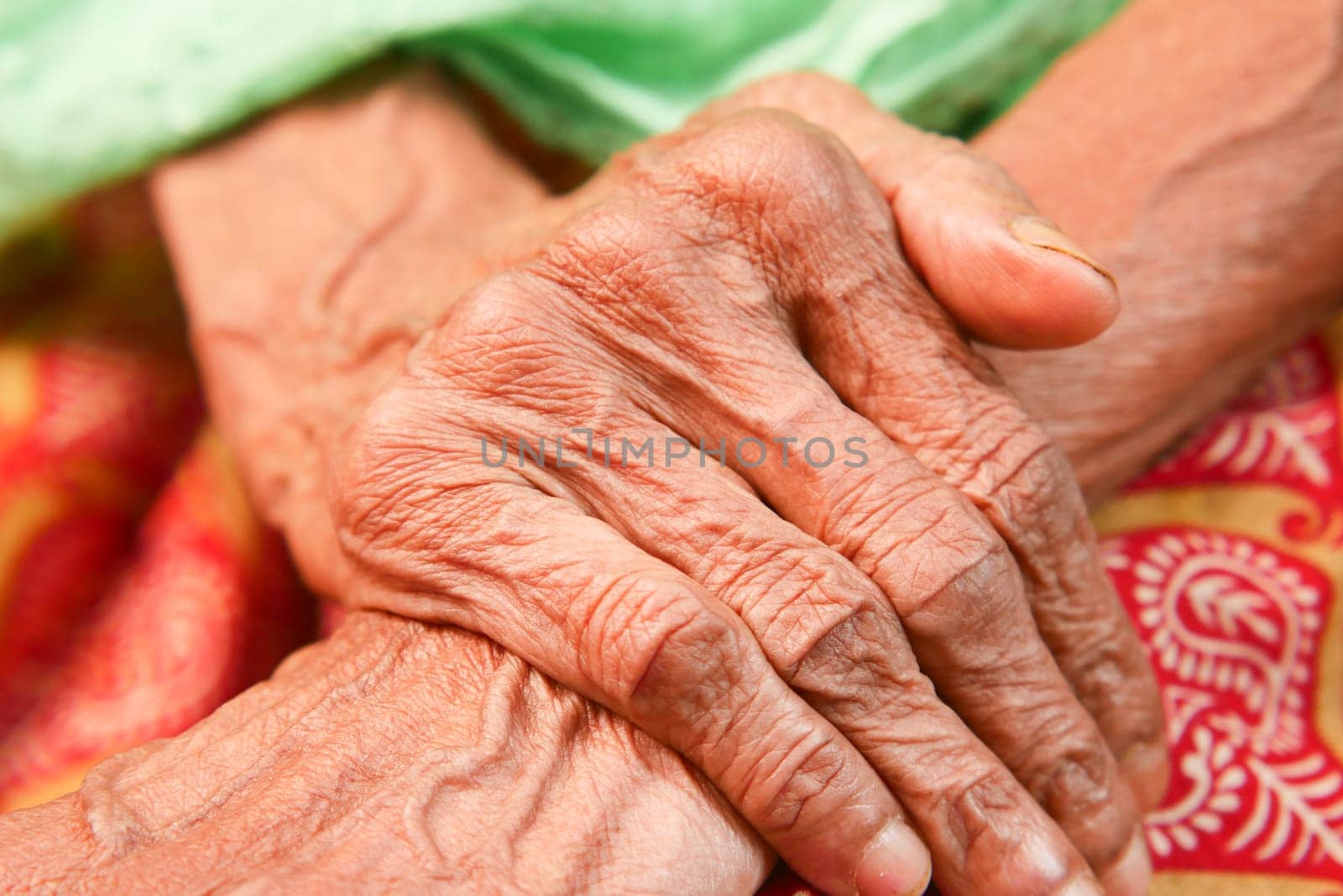 An elderly person's hands are clasped together, showing age and wisdom.
