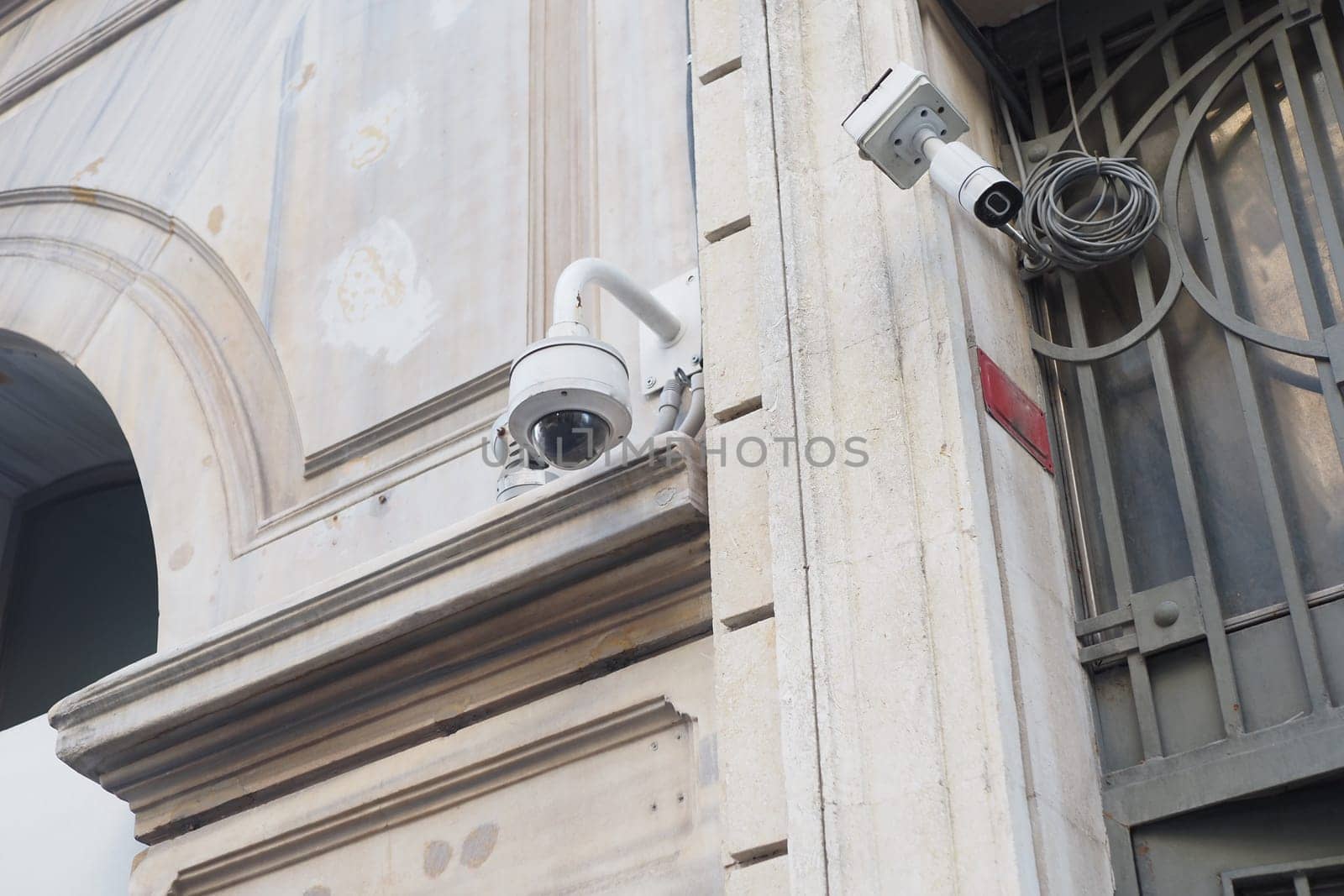 Two security cameras are positioned on a building corner with a textured wall.