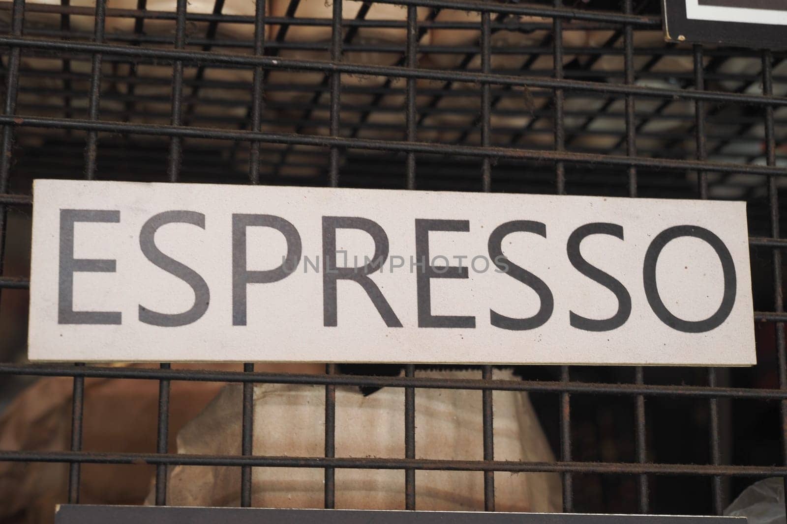 A prominent sign for espresso is showcased in an energetic cafe environment.