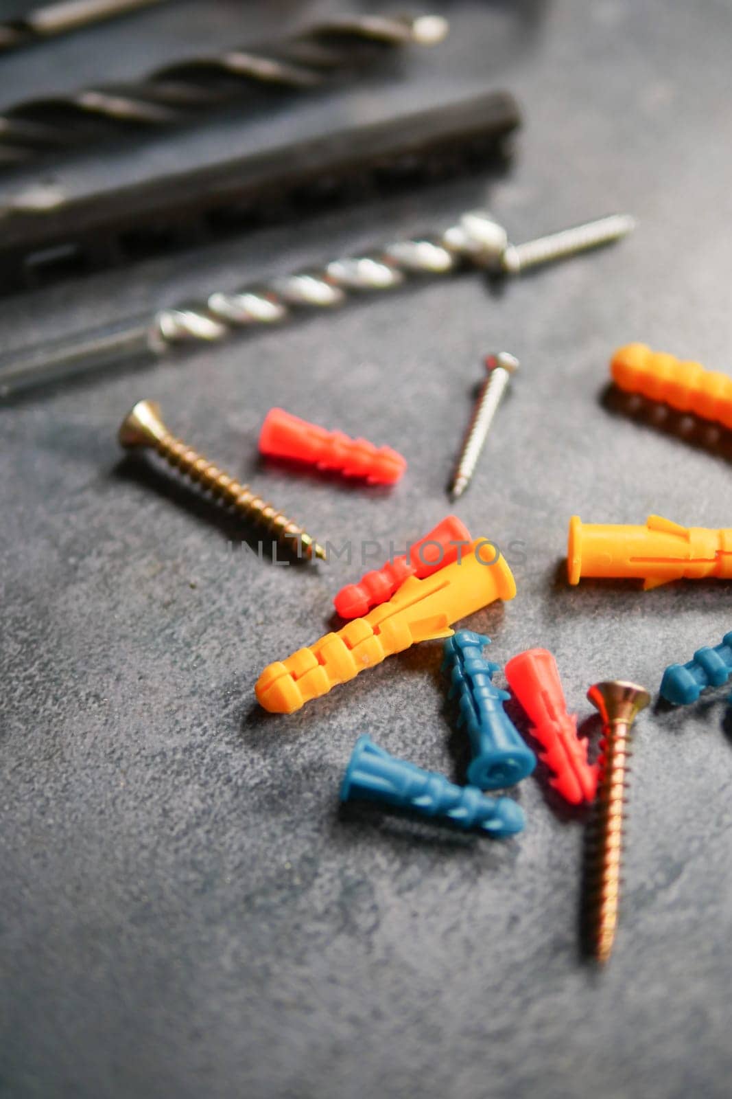 Various screws and anchors in bright colors are spread out on a work surface.