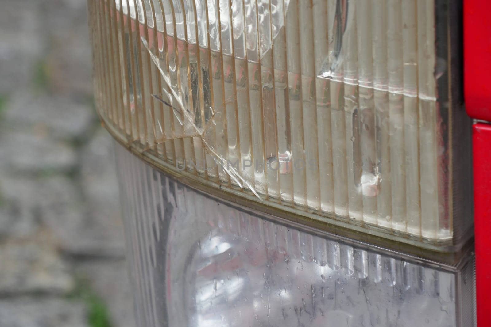 Close view of a cracked tail light reflecting light on cobblestones