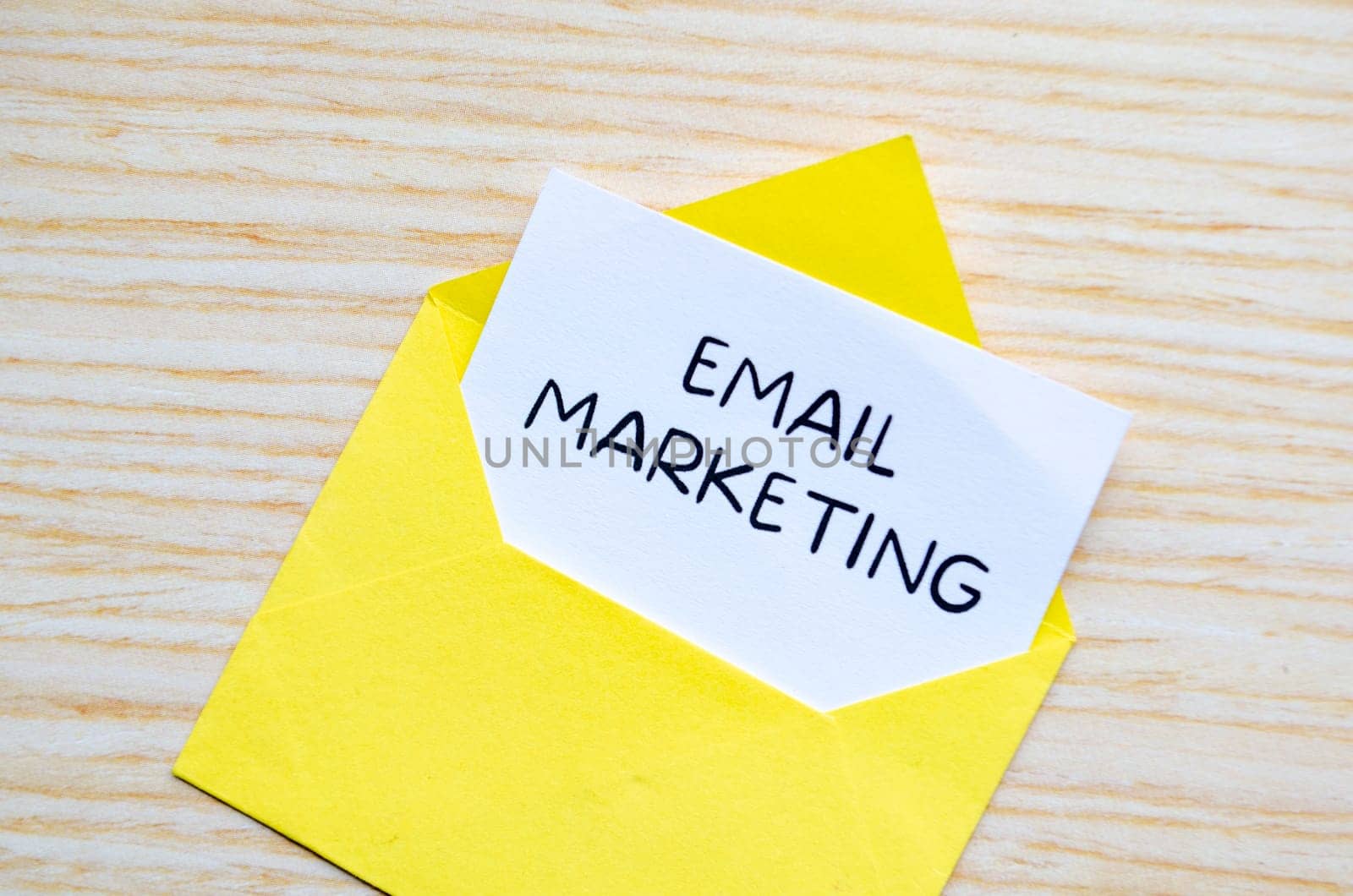 Email marketing text on white notepad inside a yellow envelope. Making money online concept.