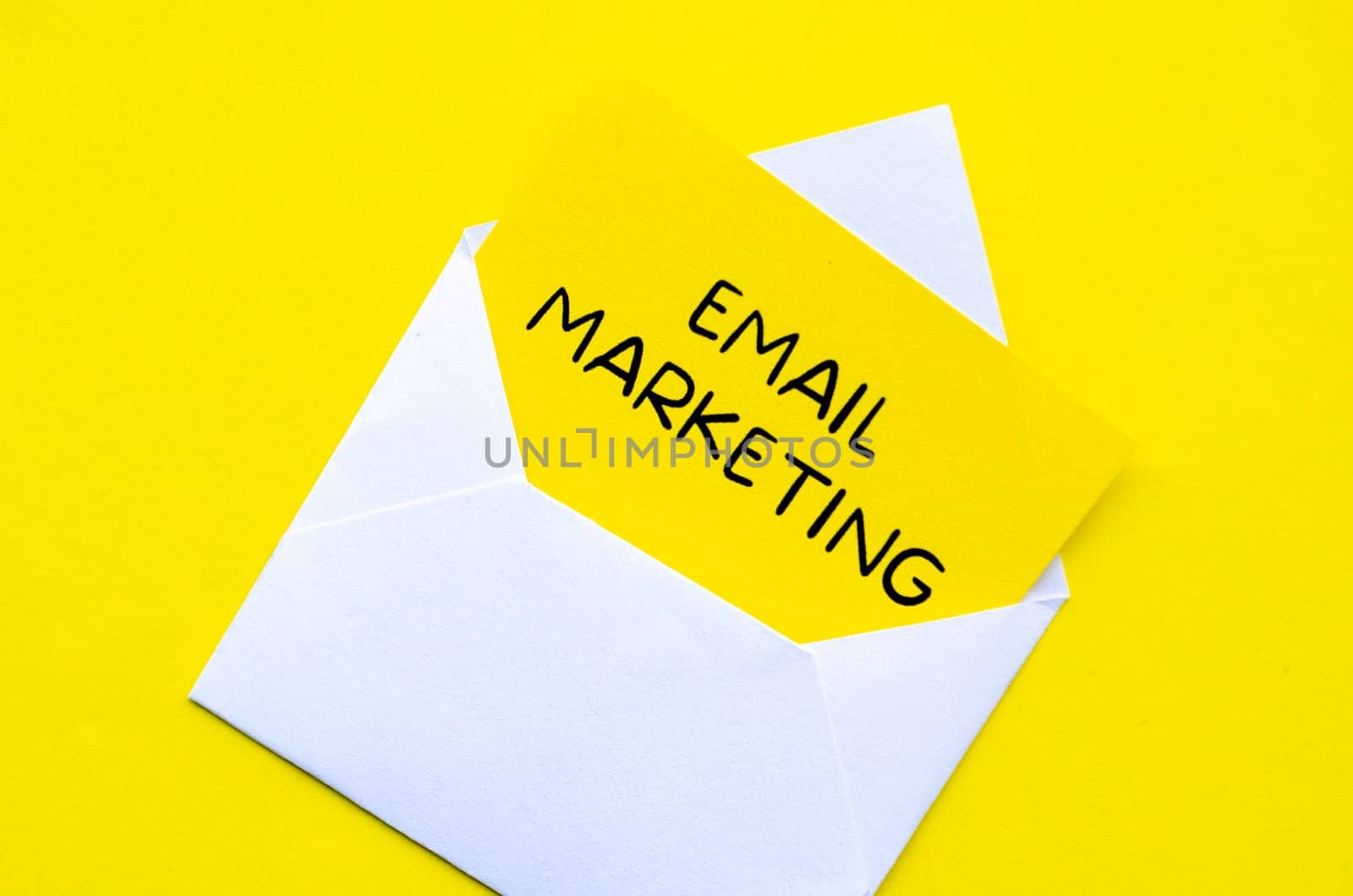 Email marketing text on yellow notepad inside a white envelope. Making money online concept.