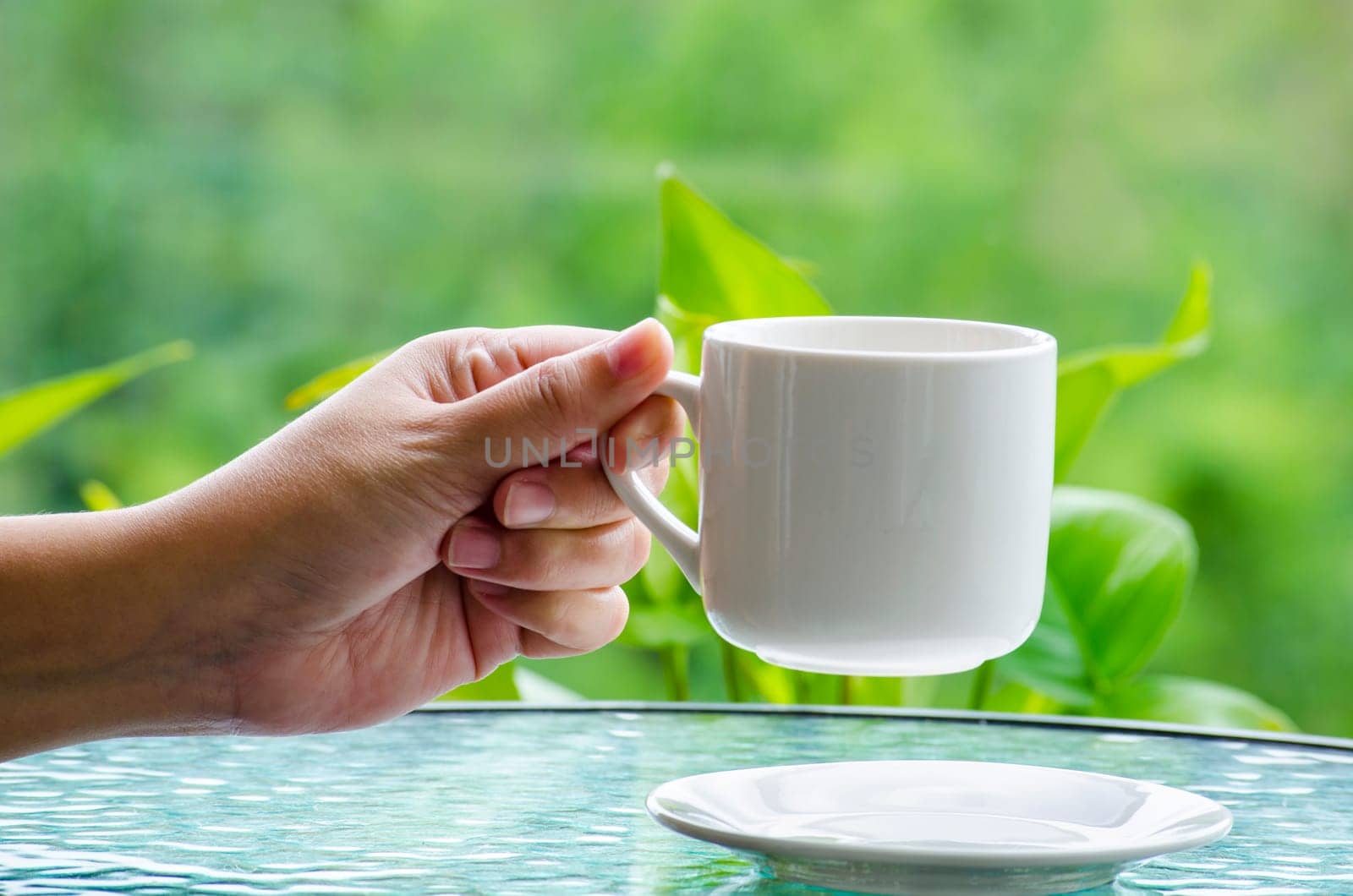 Hand holding a white cup with customizable space for mockup or text. Mockup concept