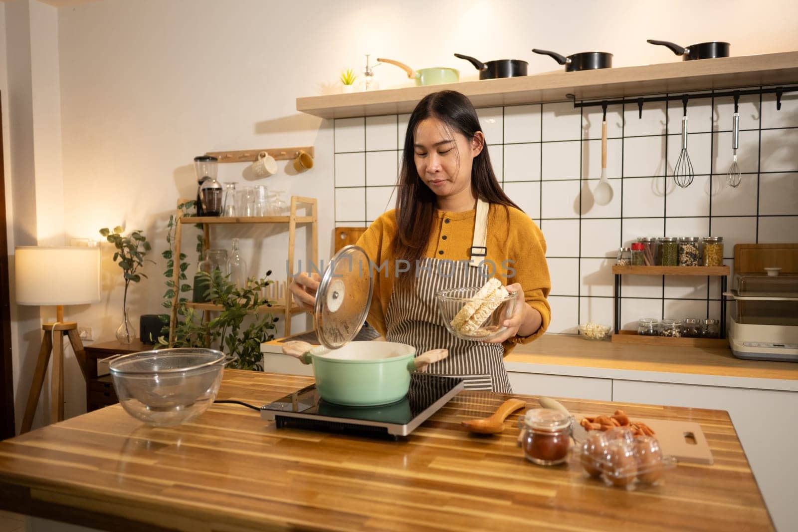 Happy young woman preparing instant noodles in a stylish modern kitchen.