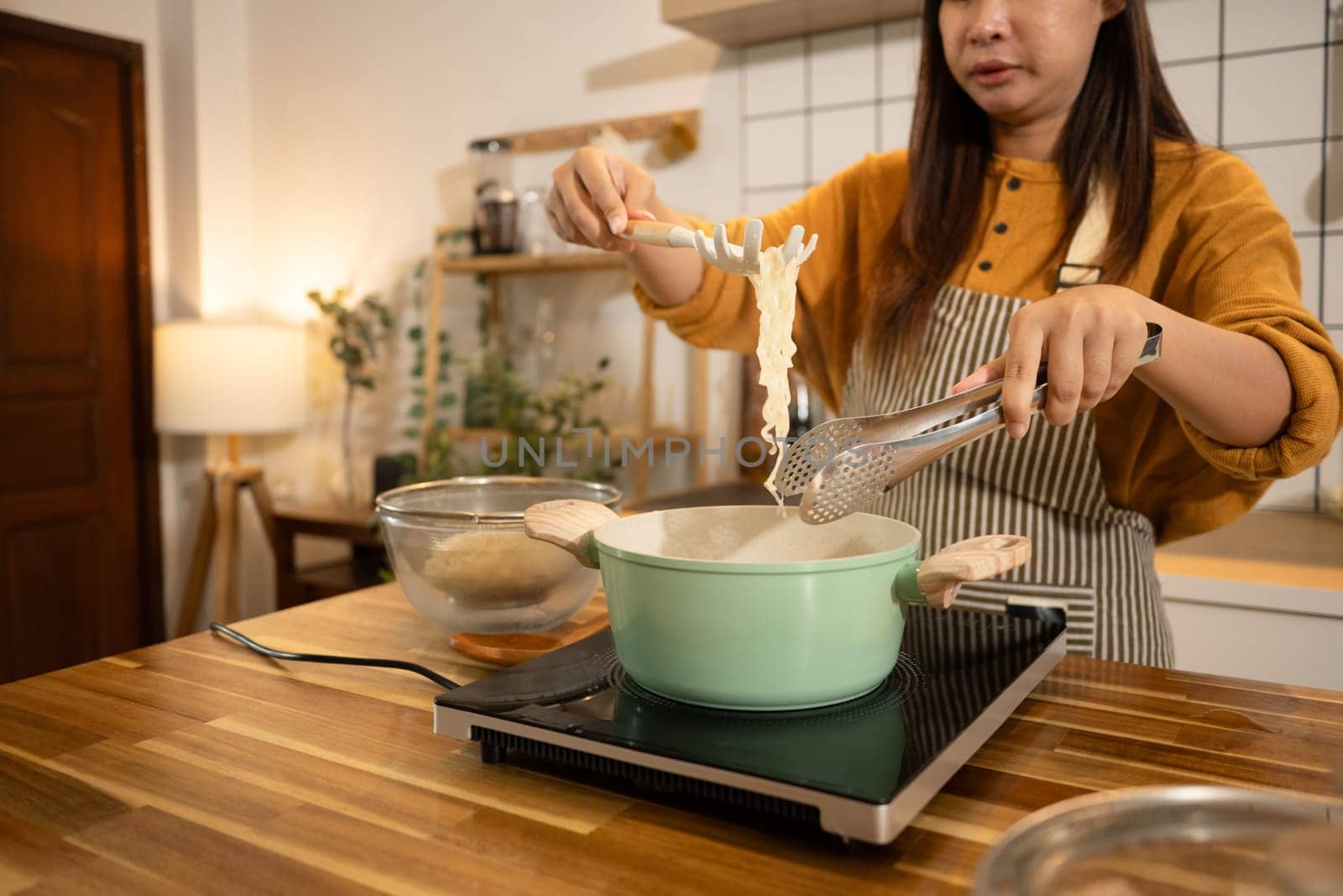 Happy young woman preparing instant noodles in a stylish modern kitchen.