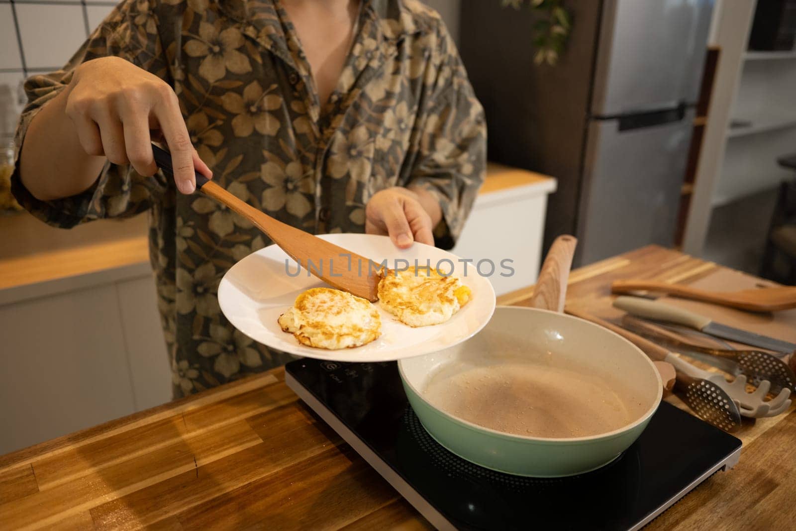Man preparing breakfast in modern kitchen, serving freshly cooked eggs on a plate.
