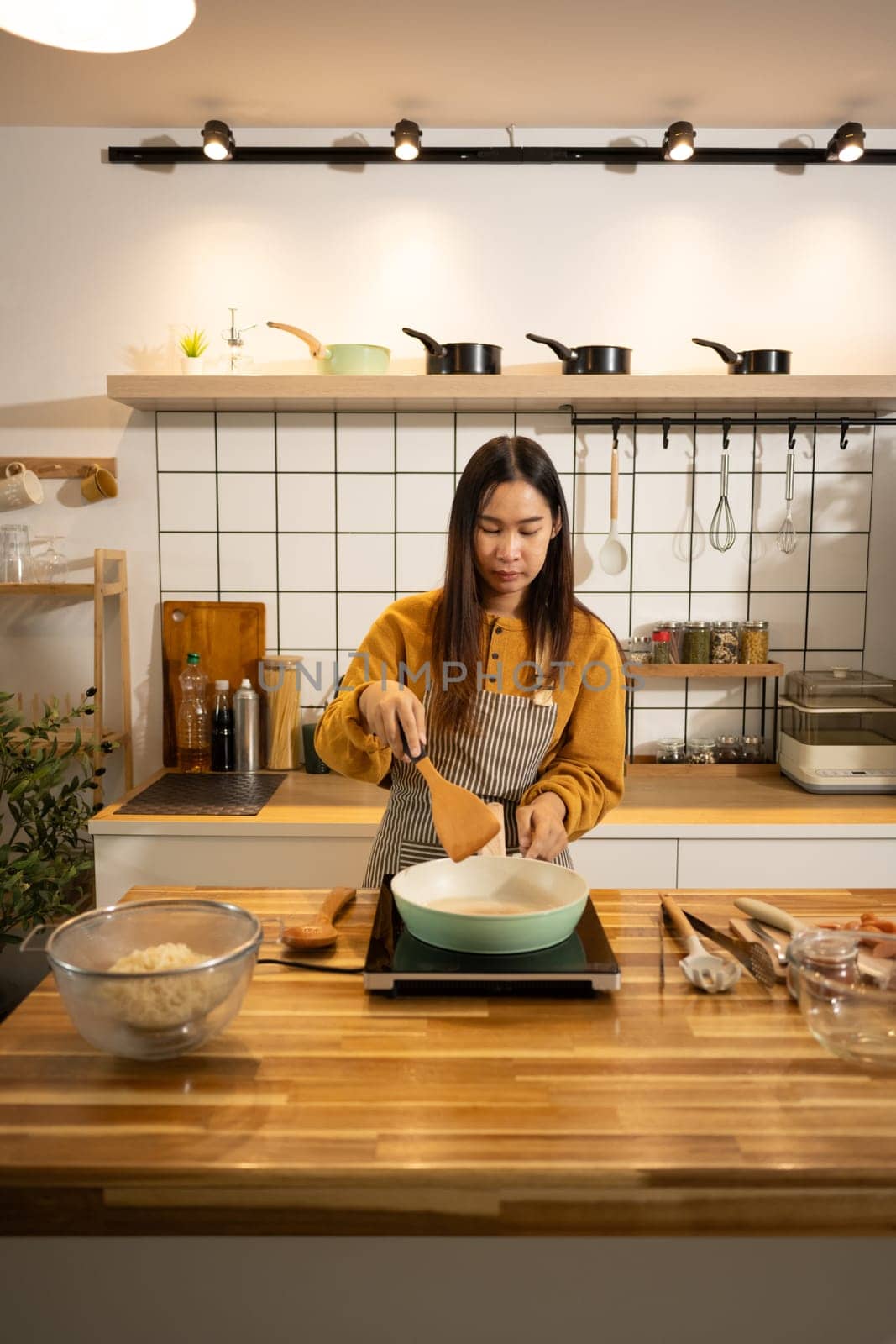 Happy young asian woman cooking in a stylish modern kitchen. Home cooking concept.