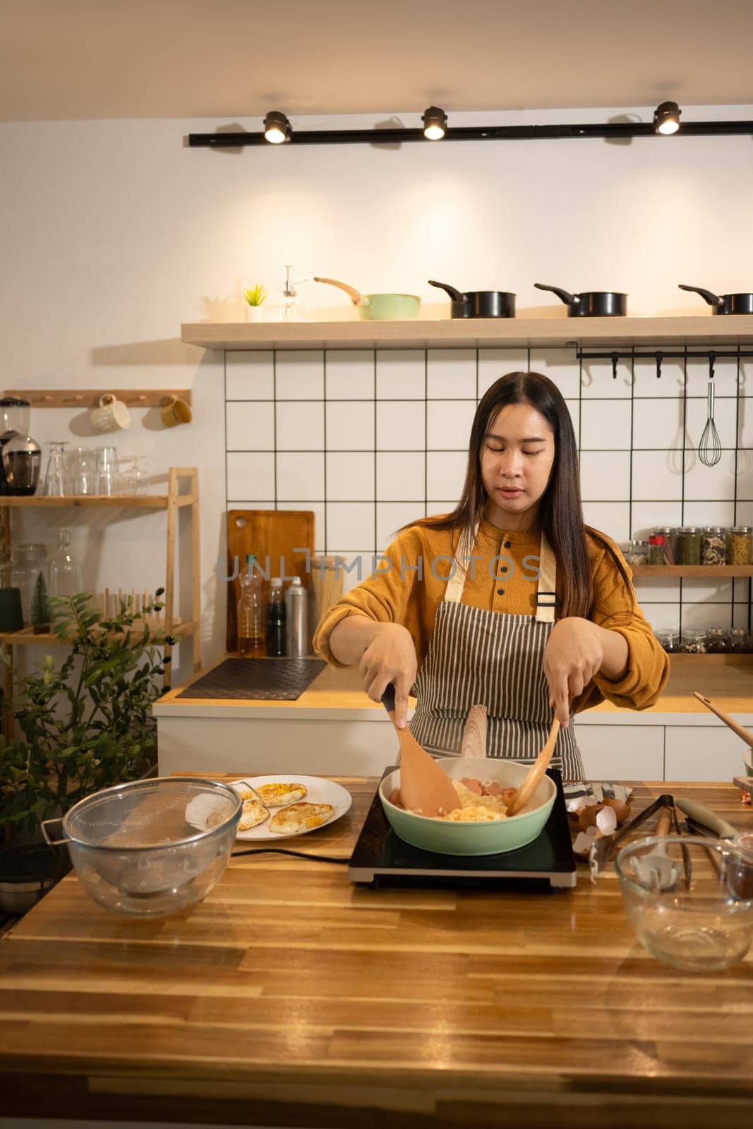 Happy young asian woman cooking in a stylish modern kitchen. Home cooking concept.