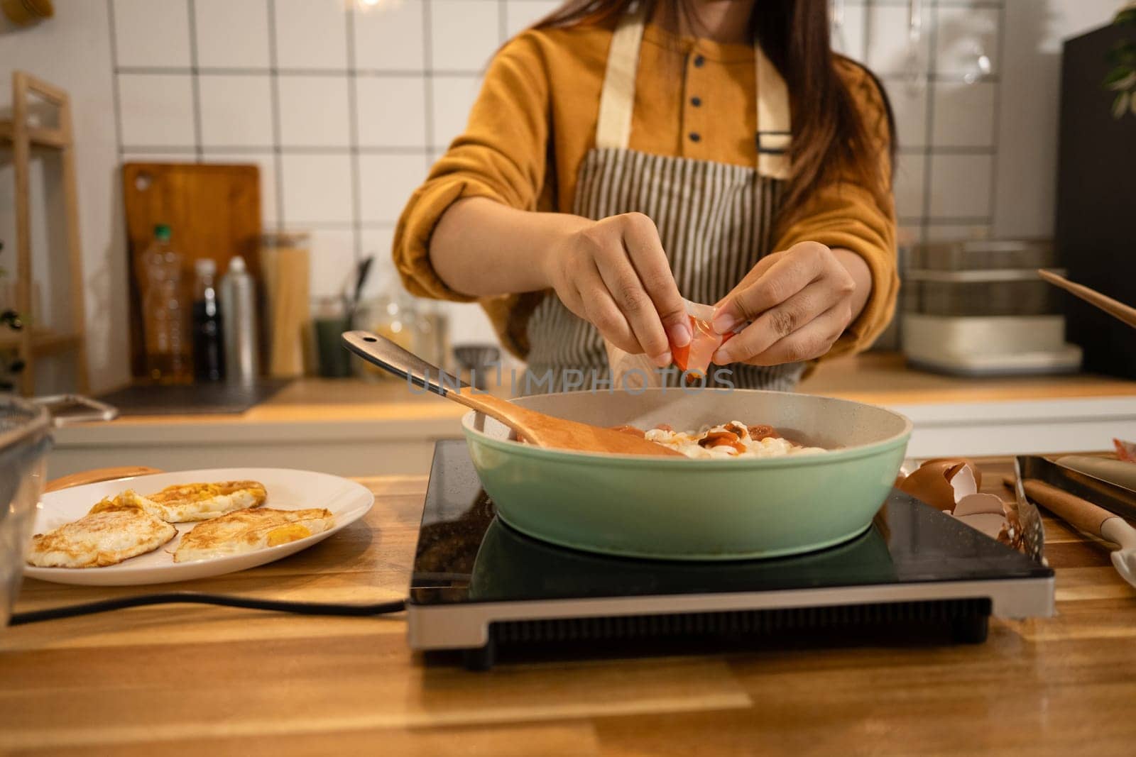 Shot of woman adding powdered seasoning to a pot of instant noodles and sausages.