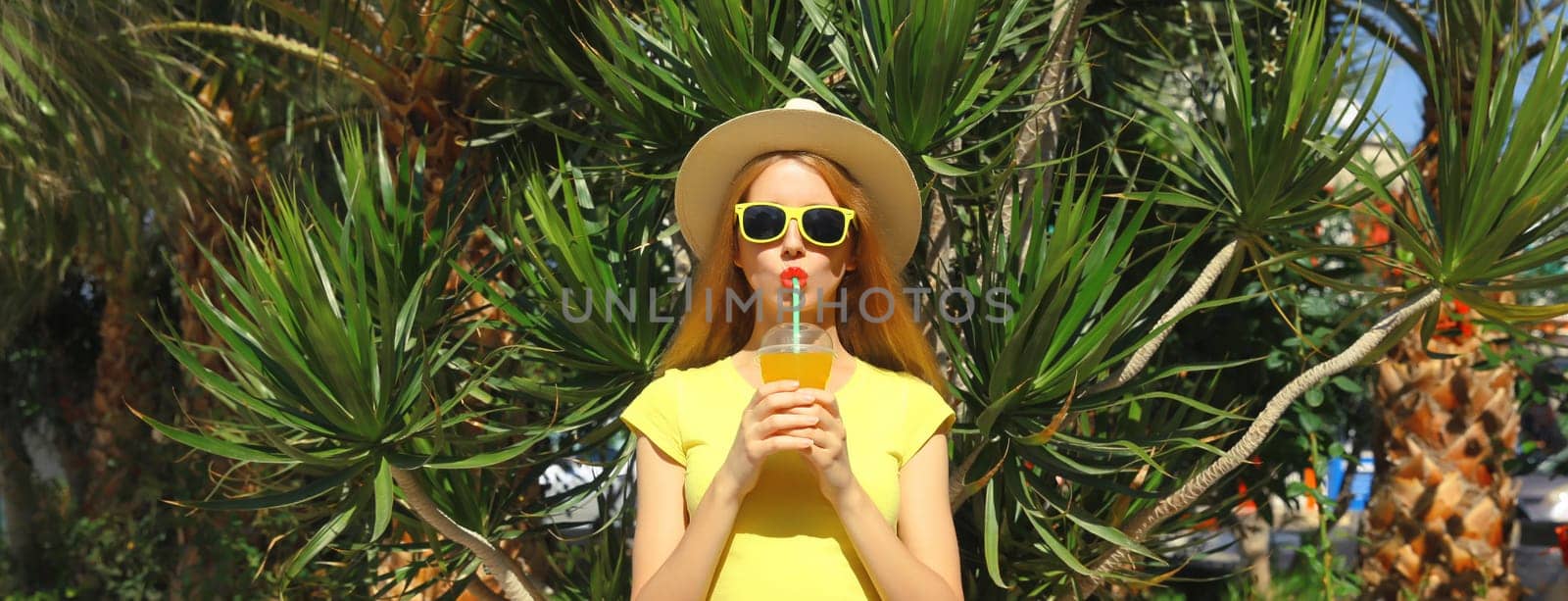 Summer vacation, tourism, happy young woman drinking fresh juice in straw tourist hat standing on the beach with palm trees