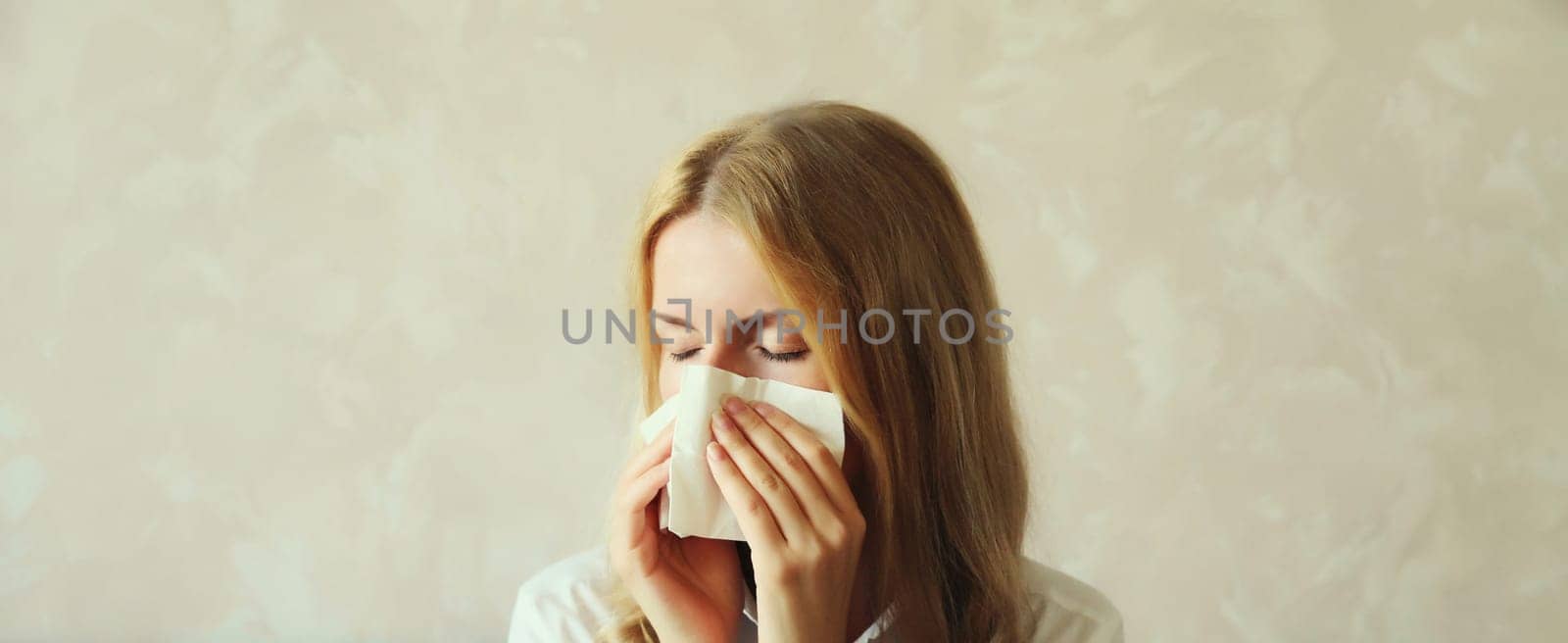 Sick exhausted young woman sneezing blow nose using tissue, unhealthy suffering girl feels unwell at home