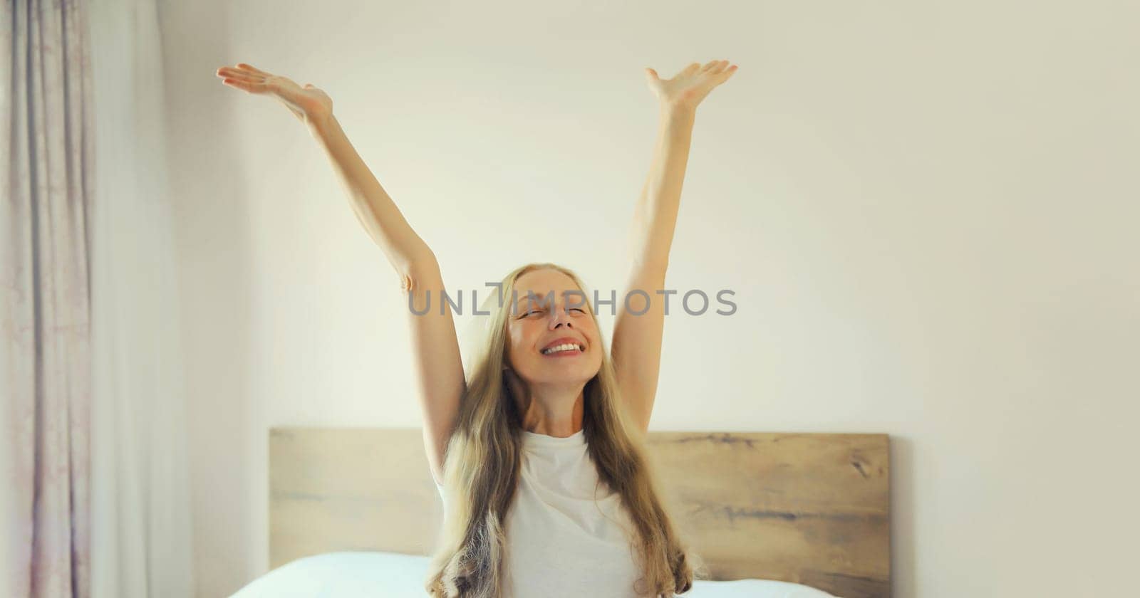 Healthy sleep, happy joyful relaxed woman wakes up lying on the bed in bedroom at home