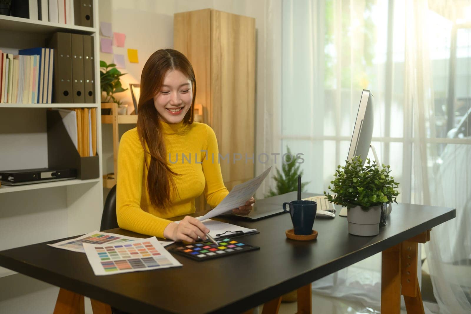 Smiling young graphic designer working with color swatches in a creative office.