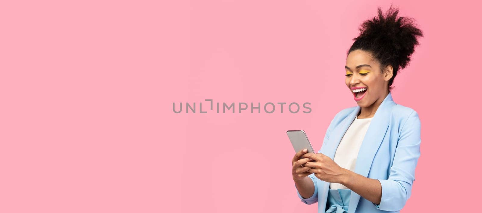 Amazing Application. Happy young black woman using cell phone isolated over pastel pink studio wall, copyspace