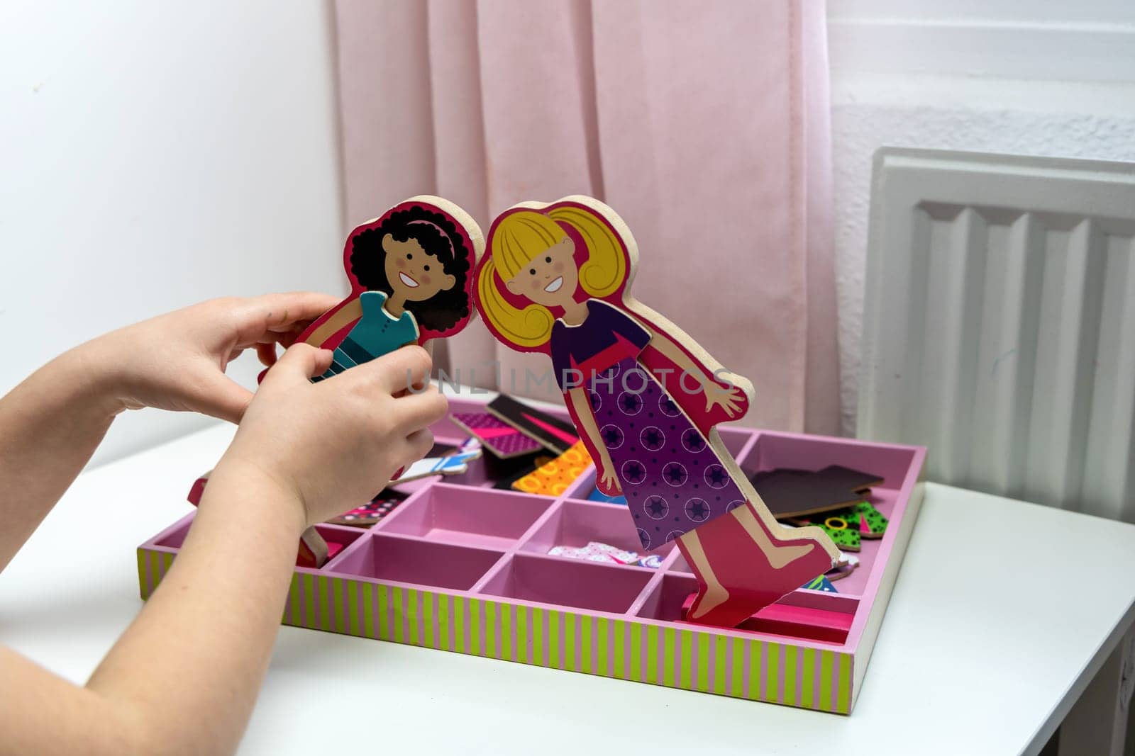 Girl dresses wooden dolls. Children's entertaiment game. High quality photo