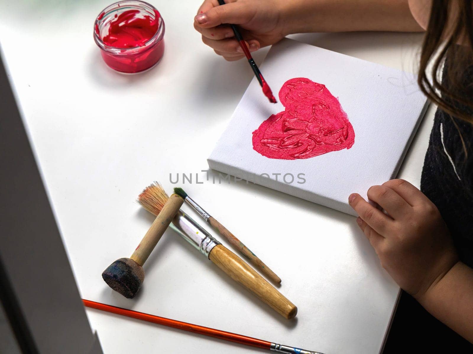 The child paints a red heart. High quality photo