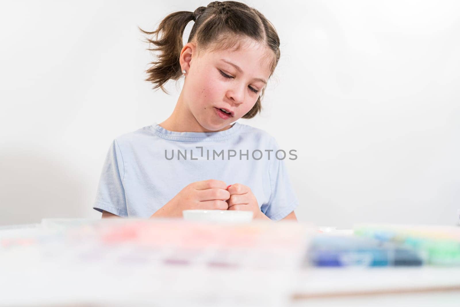 Little girl enjoys crafting colorful bracelets with vibrant clay beads set.