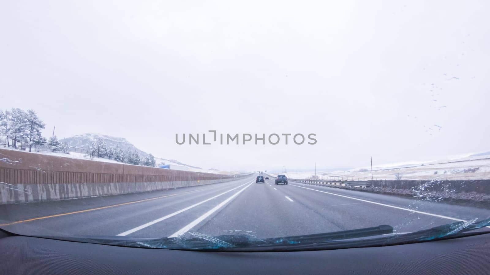 The open highway invites a peaceful drive, with snow-clad pines lining I-25 as the journey continues from Denver towards Colorado Springs on a snowy day.