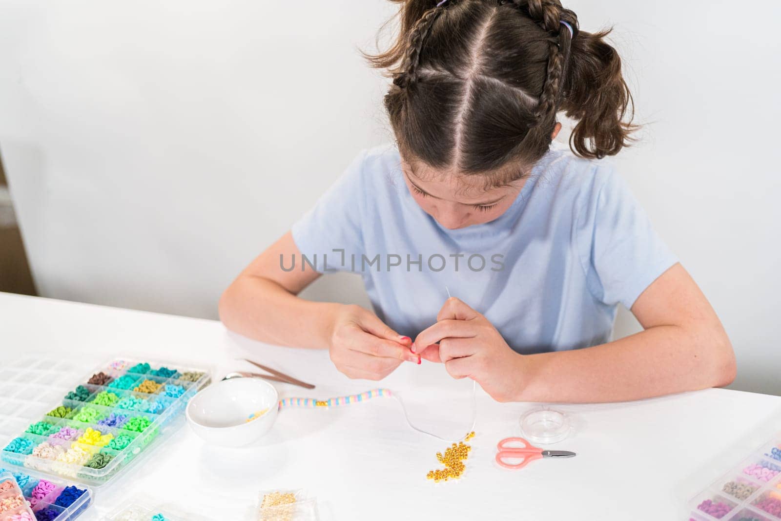 Little girl enjoys crafting colorful bracelets with vibrant clay beads set.
