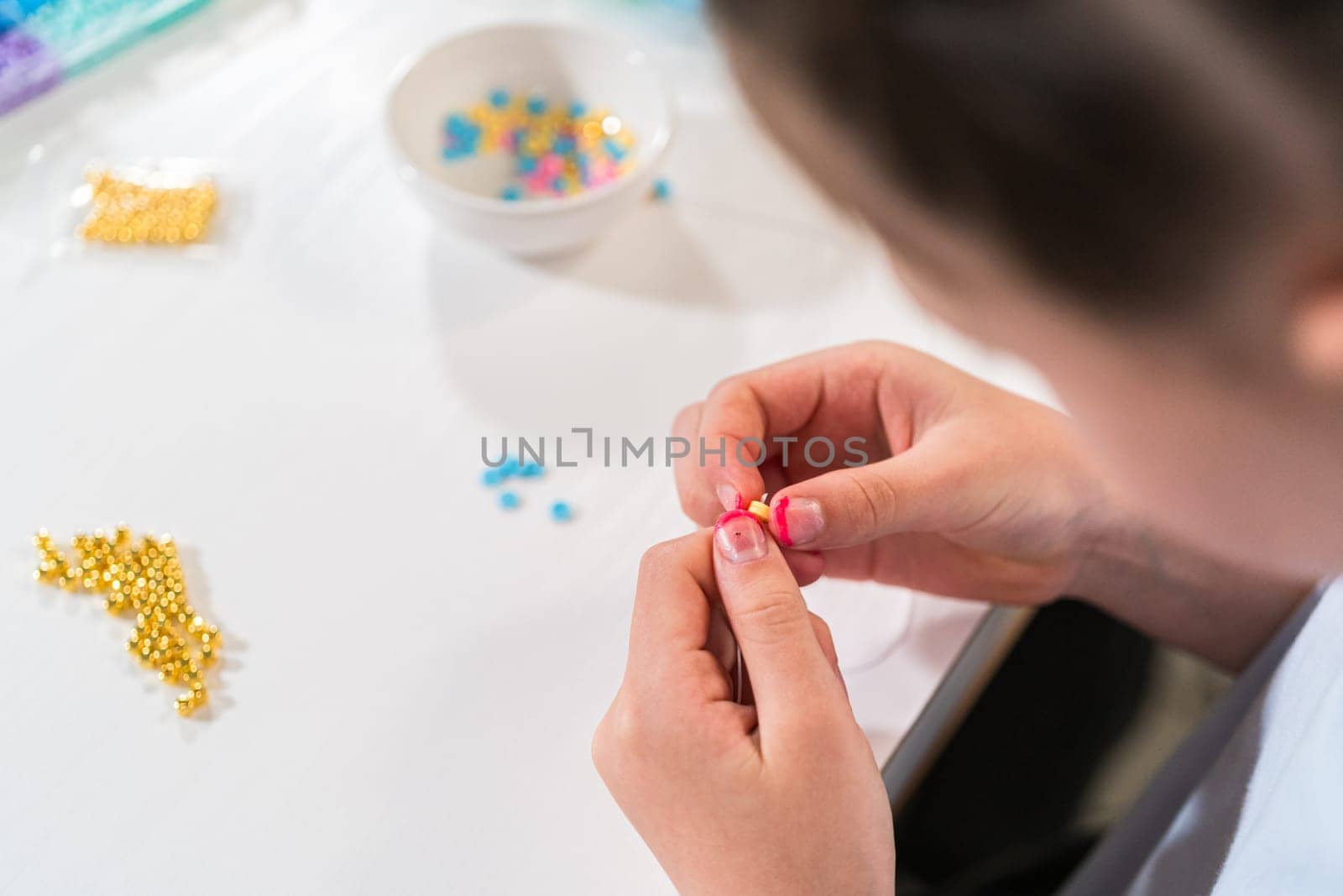 Little girl enjoys crafting colorful bracelets with vibrant clay beads set.