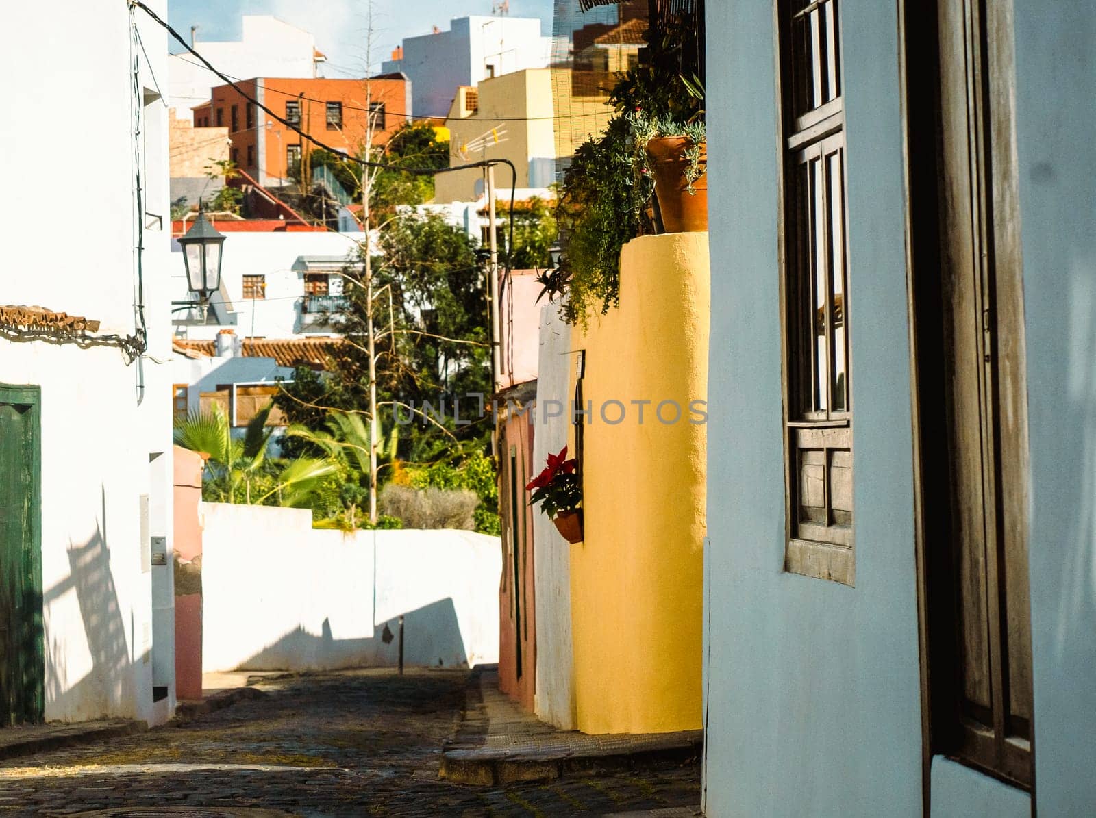 A beautiful picturesque street of the old town in the sun, houses with yellow and white walls, vintage windows and street lamps in a small village among the mountains.