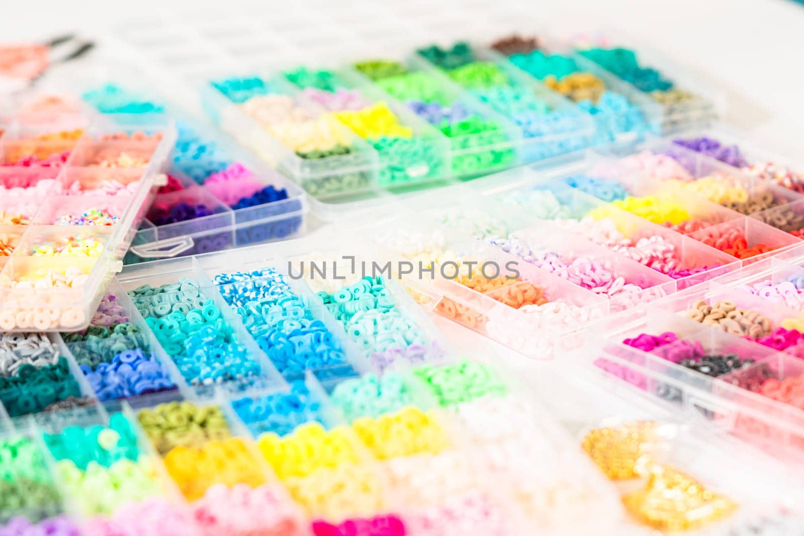 Assorted clay bead boxes neatly arranged on a white table, awaiting a creative kids' craft project.