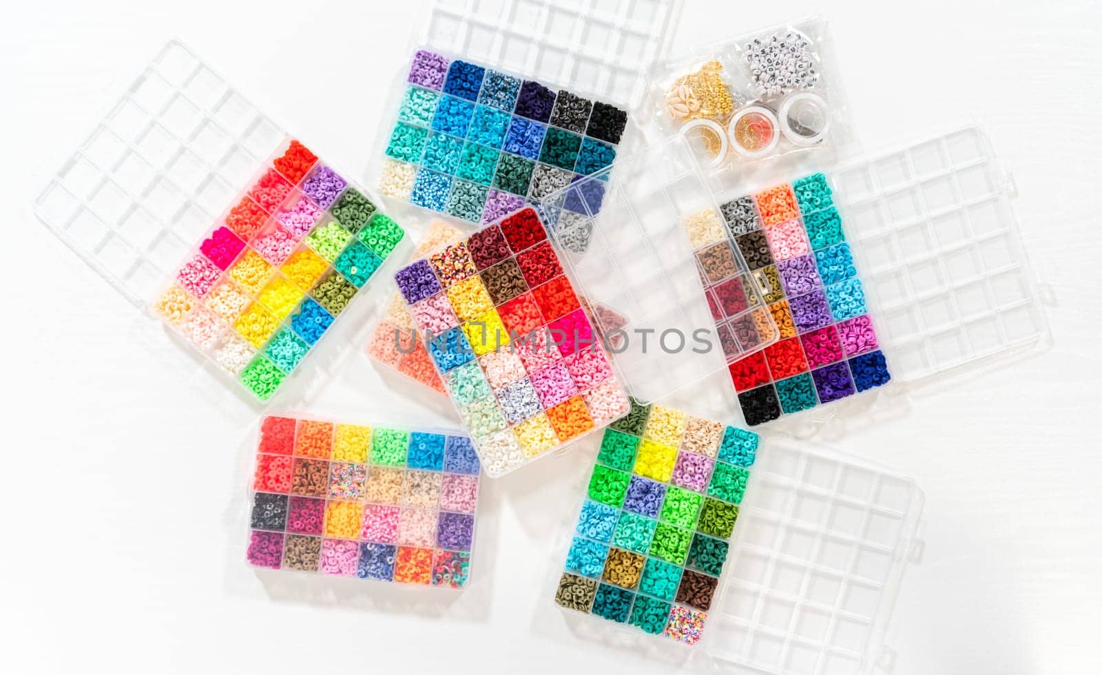 Flat lay. Assorted clay bead boxes neatly arranged on a white table, awaiting a creative kids' craft project.
