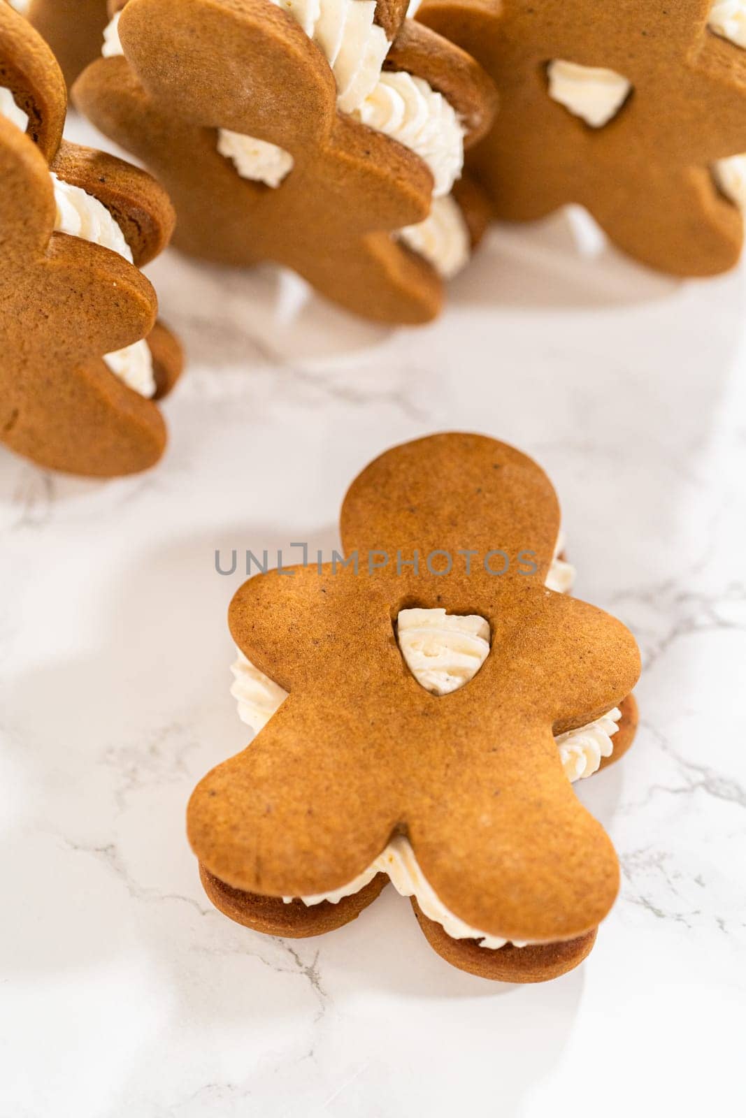 Gingerbread cookies filled with eggnog buttercream stand out, their rich hue complementing the eggnog buttercream, against a gentle background. These festive treats exude a homemade allure.