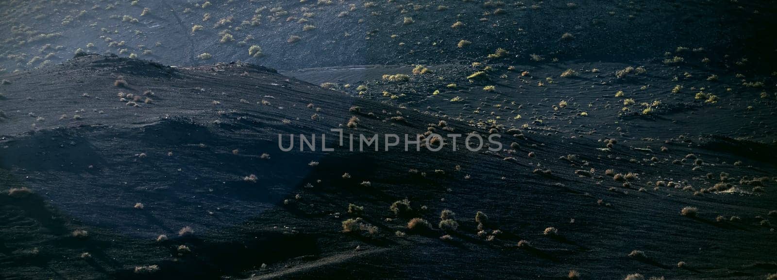 Black fossilized lava formations, basalt rocks close-up at the foot of a volcano on a volcanic beach.