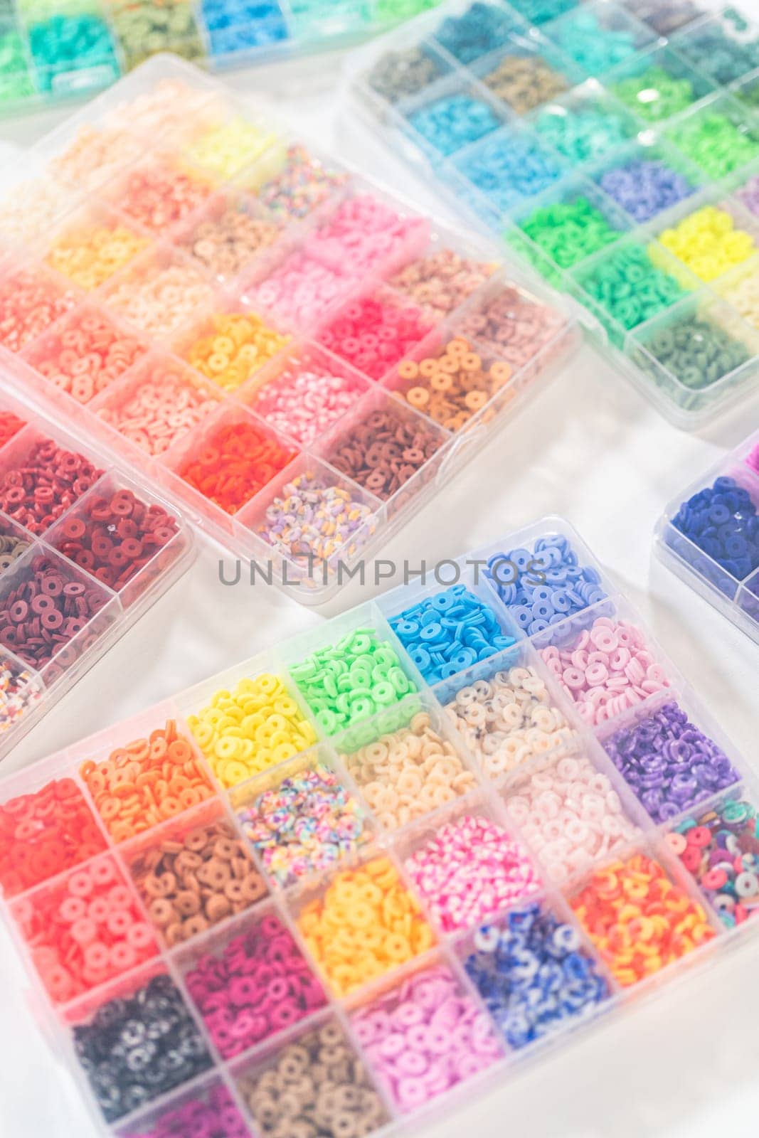 Assorted clay bead boxes neatly arranged on a white table, awaiting a creative kids' craft project.