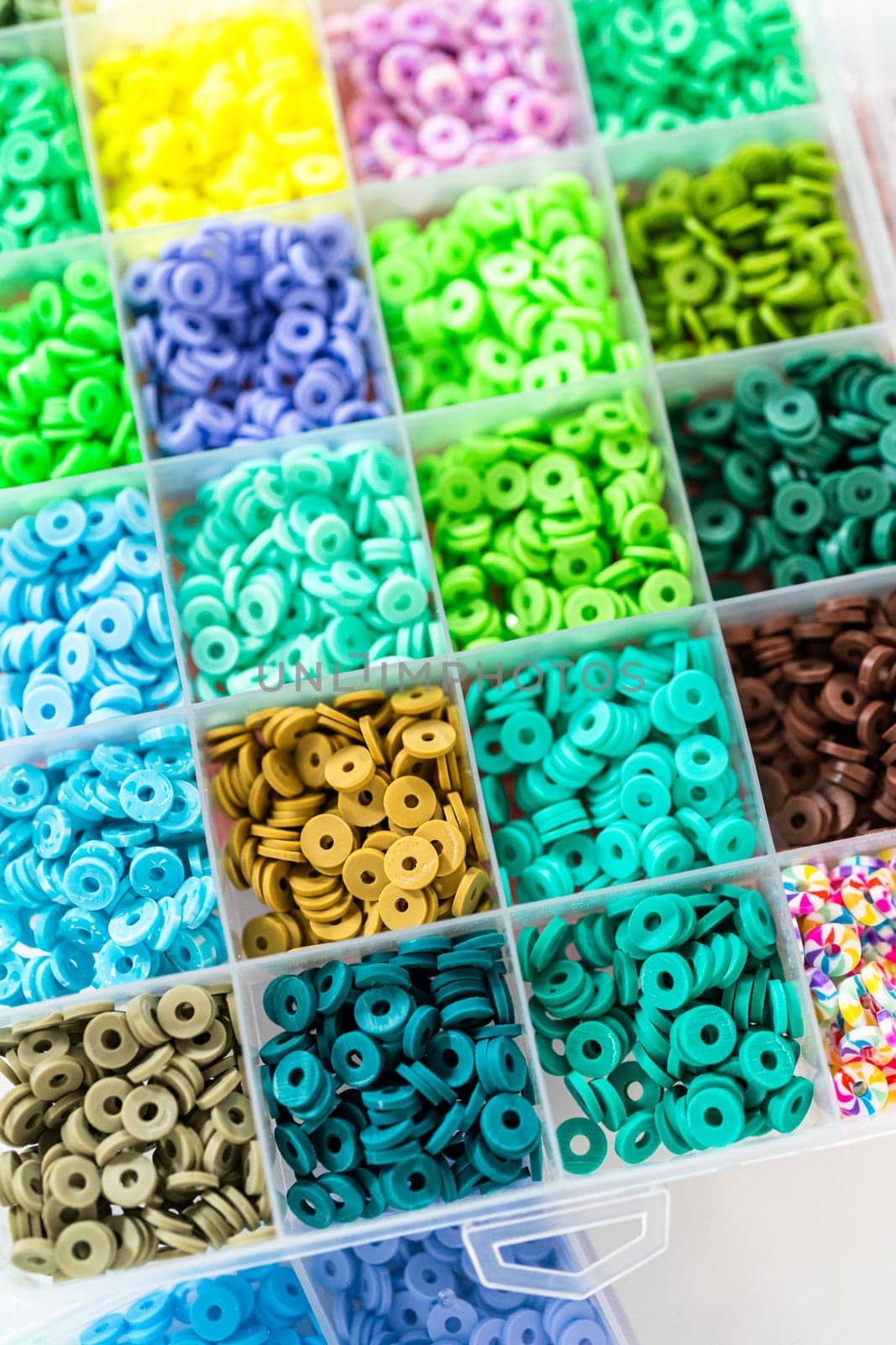Assorted clay bead boxes neatly arranged on a white table, awaiting a creative kids' craft project.