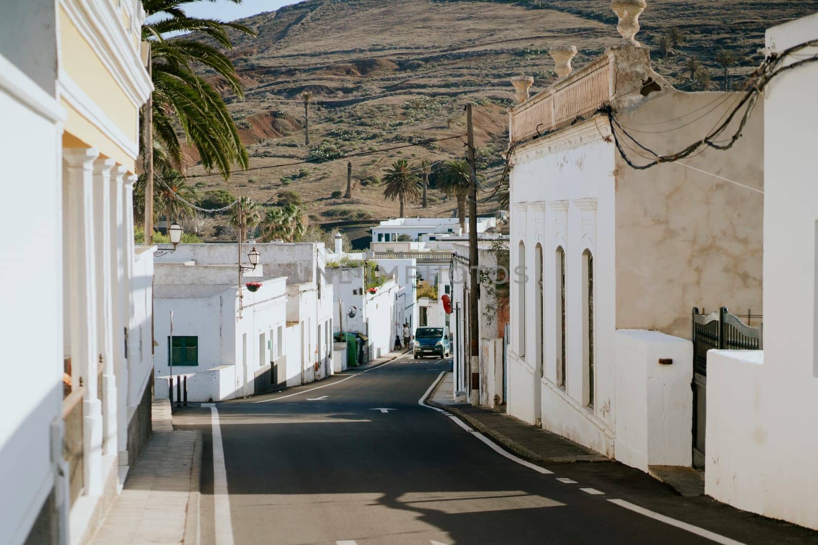 Picturesque streets of a small cozy town with white houses against the backdrop of mountains, view of the road among beautiful buildings on the island of Lanzarote, Canary Islands.
