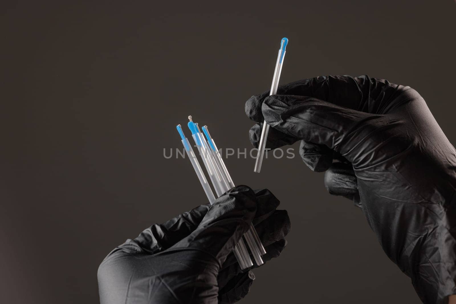concept dry needling method. Close-up of black-gloved hands holding sterile acupuncture needles in protective tubes, symbolizing alternative medicine, precision, and healthcare.