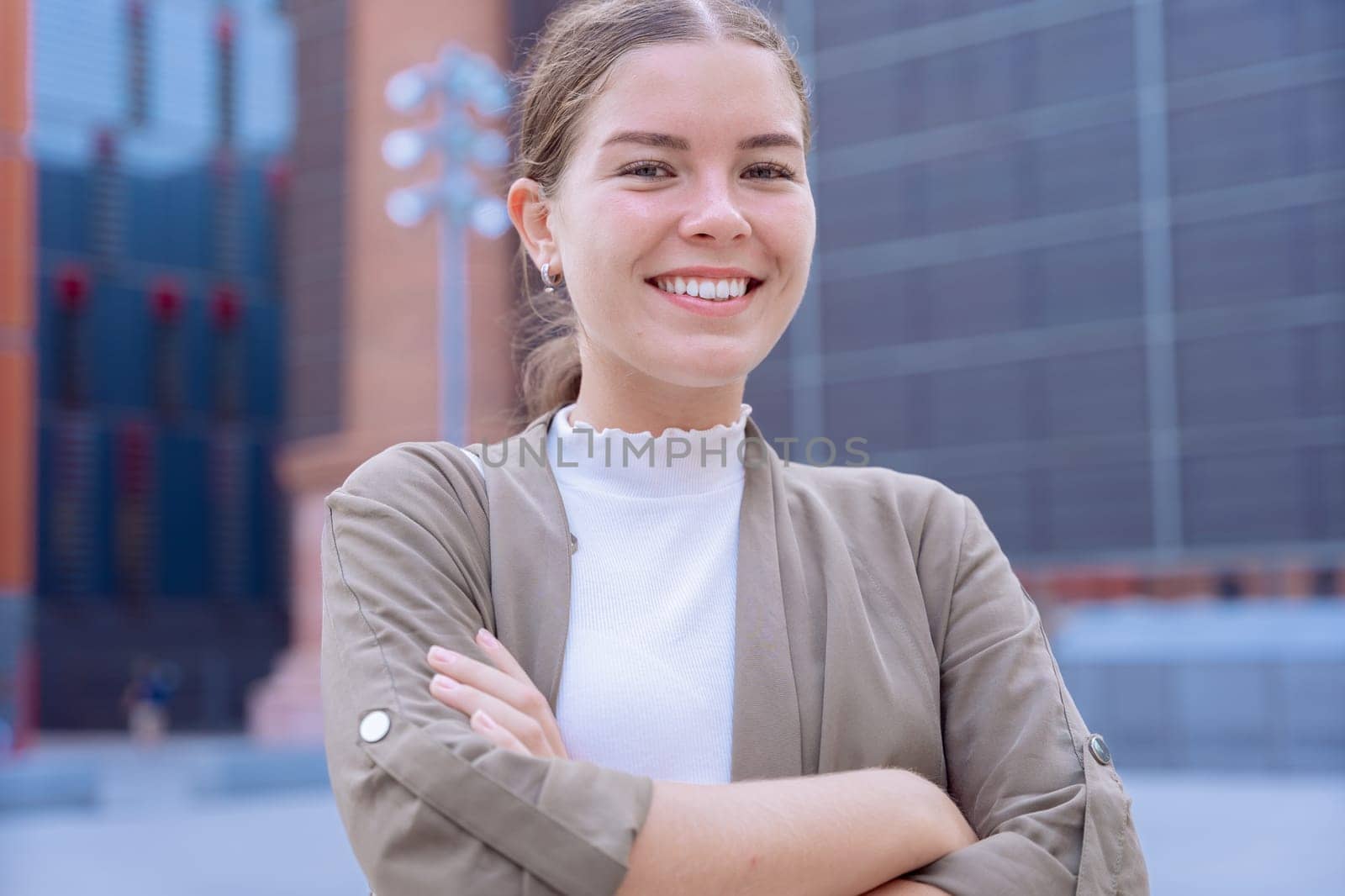 A smiling young businesswoman with her arms crossed looking at the camera. She looks confident and approachable, making her an ideal image for business, leadership, success, and empowerment concepts.